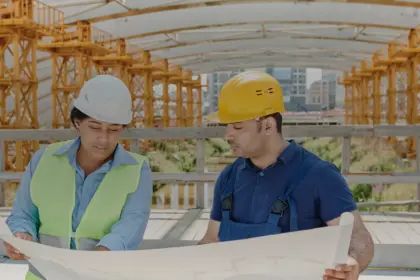 Deux professionnels du chantier examinent un plan de bâtiment